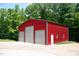 Red metal outbuilding/shed on a concrete pad with three garage doors, a Personal door, and a window at 3750 Mebane Rogers Rd, Mebane, NC 27302