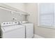 Functional laundry room with white washer and dryer, shelving, and natural light from the window at 3914 Old Chapel Hill Rd, Durham, NC 27707