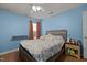 Cozy blue bedroom featuring a bed, ceiling fan, window with curtains, and a night stand at 4216 Lake Woodard Dr, Raleigh, NC 27604