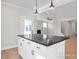 Kitchen island with a black countertop, white cabinets, and hardwood floors in an open floorplan at 448 Golden Dragonfly St, Wake Forest, NC 27587