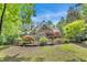 Beautiful backyard featuring a brick home, fenced-in yard, deck, manicured landscaping, and lush greenery at 4817 Fox Branch Ct, Raleigh, NC 27614