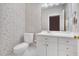 Bathroom featuring toilet and vanity with white cabinets, sink, and neutral-toned walls with patterned wallpaper at 4817 Fox Branch Ct, Raleigh, NC 27614