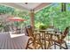 Inviting deck with wooden table, chairs, brick post, fan, umbrella, grill, and surrounded by lush trees at 4817 Fox Branch Ct, Raleigh, NC 27614