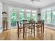 Sunlit dining area features a wood table, hardwood floors, and expansive windows with backyard views at 4817 Fox Branch Ct, Raleigh, NC 27614
