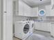 Bright laundry room with white cabinets, modern washer and dryer, and a round window at 4817 Fox Branch Ct, Raleigh, NC 27614