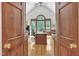 View of the office through double doors, featuring a large window, vaulted ceilings, and a hardwood floor at 4817 Fox Branch Ct, Raleigh, NC 27614