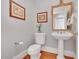 Elegant powder room with pedestal sink, decorative mirror, and hardwood floors at 4817 Fox Branch Ct, Raleigh, NC 27614