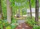 A serene backyard with a stone path, lush greenery, and a detached garage at 5720 Brushy Meadows Dr, Fuquay Varina, NC 27526