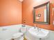 Cozy half bathroom with pedestal sink, wooden framed mirror, and paneled wainscoting at 5720 Brushy Meadows Dr, Fuquay Varina, NC 27526