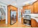 Bright kitchen with stainless steel appliances, wooden cabinets, and hardwood floors and entrance to stairs at 5720 Brushy Meadows Dr, Fuquay Varina, NC 27526
