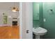 A green powder room with a pedestal sink, vintage mirror, and access to the living room with a fireplace at 6335 Cedar Waters Dr, Raleigh, NC 27607