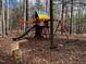 Private wooden playground with a slide, swings, and climbing structure, nestled in a wooded area at 6412 Heartwood Dr, Chapel Hill, NC 27516