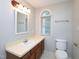 Comfortable bathroom with a cream sink with wood cabinets and a large arched window at 6756 Olde Province Ct, Raleigh, NC 27609