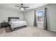 A bright bedroom with a gray bed set against soft carpet, complemented by a ceiling fan and natural light at 7584 Oakberry Dr, Raleigh, NC 27616