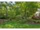 Lush backyard featuring green grass, mature trees, and lush landscaping with a wrought iron fence at 800 E Forest Hills Blvd, Durham, NC 27707