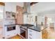 Modern kitchen with stainless steel appliances, white cabinetry, and brick accent wall over a hardwood floor at 800 E Forest Hills Blvd, Durham, NC 27707