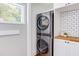 This laundry area features a stacked washer and dryer, white cabinetry, butcher block countertops, and a window for natural light at 800 E Forest Hills Blvd, Durham, NC 27707