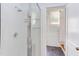 Clean shower with a glass door, white tile, and glass shelving for organized storage at 800 E Forest Hills Blvd, Durham, NC 27707