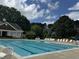Community pool with seating and lounge chairs for residents, set amongst mature trees and shrubbery at 825 Federal House Ave, Wake Forest, NC 27587