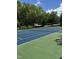 Well-maintained community tennis court with a blue and green playing surface surrounded by mature shade trees at 825 Federal House Ave, Wake Forest, NC 27587
