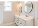 Bright bathroom features a double vanity, round mirrors, and a sunlit window at 8709 Kimalden Ct, Wake Forest, NC 27587