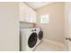 Modern laundry room with white cabinets, tile floors, and front-loading washer and dryer at 8709 Kimalden Ct, Wake Forest, NC 27587