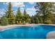 Sparkling blue pool with stone fire pit and Adirondack chairs surrounded by lush landscaping at 8709 Kimalden Ct, Wake Forest, NC 27587