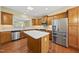 Open-concept kitchen boasts stainless steel appliances, wood cabinets, and a center island with seating at 923 Peltier Dr, Cary, NC 27519