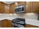 Close-up of kitchen with stainless steel oven, cooktop, microwave and quartz countertops at 923 Peltier Dr, Cary, NC 27519