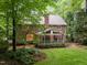 Backyard view of brick house with screened in porch and mature trees at 1003 Gloucester Ct, Chapel Hill, NC 27516