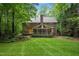 Backyard showcasing a brick house, a screened-in porch, and a well-maintained lawn surrounded by trees and landscaping at 1003 Gloucester Ct, Chapel Hill, NC 27516