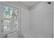 Bright bathroom featuring a shower over tub with a window and white tile at 1003 Gloucester Ct, Chapel Hill, NC 27516