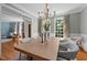 A stylish dining room with a large wooden table, comfortable seating, and natural light from many large windows at 1003 Gloucester Ct, Chapel Hill, NC 27516
