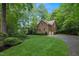 A brick home with well-manicured front lawn and a circular driveway, surrounded by lush trees at 1003 Gloucester Ct, Chapel Hill, NC 27516