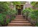 Inviting front entrance with brick steps and wrought iron railing, surrounded by lush greenery at 1003 Gloucester Ct, Chapel Hill, NC 27516