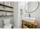 Modern powder room featuring floating shelves, rustic wood accents, white vessel sink, and black round mirror at 1008 Wolfs Bane Dr, Apex, NC 27539