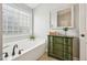 Bathroom with soaking tub, window, tile floor, and vintage-style dresser at 1008 Wolfs Bane Dr, Apex, NC 27539