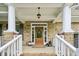 Charming front porch with brick flooring, white columns, and a decorative wooden front door at 1008 Wolfs Bane Dr, Apex, NC 27539