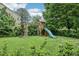 Backyard with a wooden swing set, slide, and lush green grass at 1008 Wolfs Bane Dr, Apex, NC 27539