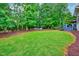 Lush backyard featuring mature trees, green grass, and a private patio area perfect for relaxation and entertainment at 101 Ironcreek Pl, Apex, NC 27539