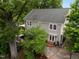 Aerial view of a grey two-story home with a lush yard, an outdoor dining area, and a paved driveway and patio at 1015 Watts St, Durham, NC 27701