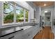 Farmhouse sink overlooking a lush backyard in an updated kitchen with white cabinets and black countertops at 1015 Watts St, Durham, NC 27701