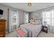 Bedroom with natural light showcases an iron bed frame, neutral walls, and three windows with white curtains at 105 Stoney Dr, Durham, NC 27703