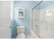 Bright bathroom with a white shower-tub, glass door, and complementary blue walls at 10516 Cokesbury Ln, Raleigh, NC 27614