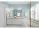 Bright bathroom with dual vanity, framed mirror, and a soaking tub enclosed by glass with gold trim at 10516 Cokesbury Ln, Raleigh, NC 27614