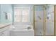 Bathroom featuring a soaking tub, a glass shower enclosure, and a bright window with white blinds at 10516 Cokesbury Ln, Raleigh, NC 27614