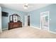 Bright bedroom with light blue walls, carpeted floor, ceiling fan, and a wooden dresser with a mirror at 10516 Cokesbury Ln, Raleigh, NC 27614
