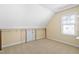 Upstairs bedroom with angled walls, carpeted floors, a window, and a small door with a white frame at 10516 Cokesbury Ln, Raleigh, NC 27614