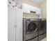 Updated laundry room with front-load washer, dryer, and ample white cabinet storage at 10516 Cokesbury Ln, Raleigh, NC 27614
