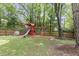 Large backyard with wooden playground set, tree coverage, and privacy fence at 106 E Delafield Ave, Durham, NC 27704